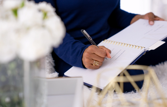 Photo of a women holding a pen and writing in a notebook