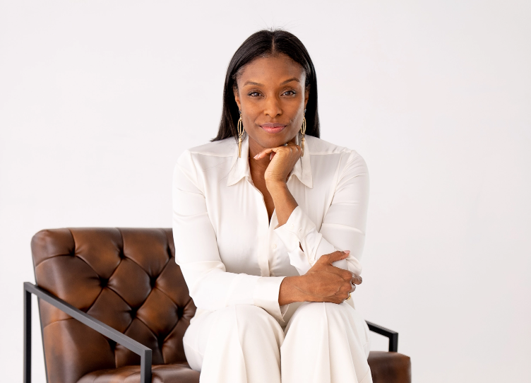 Executive coach Nicole Smith in an all white outfit sitting on a brown leather chair